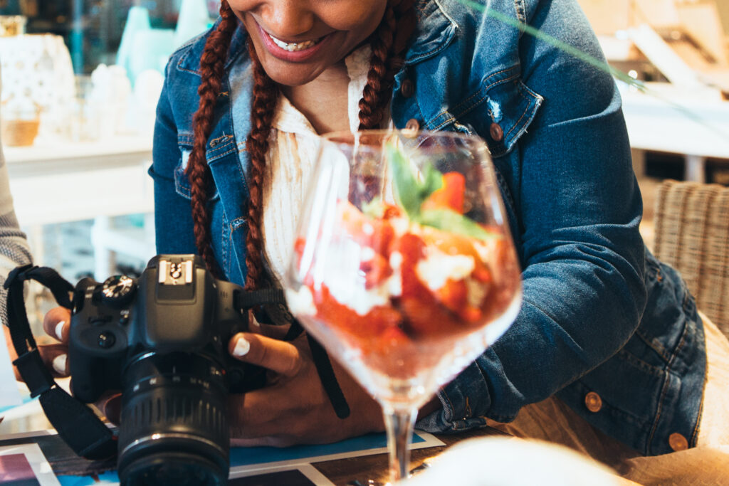 Cropped view of smiling young mixed race woman photographer working with a photo camera at agency